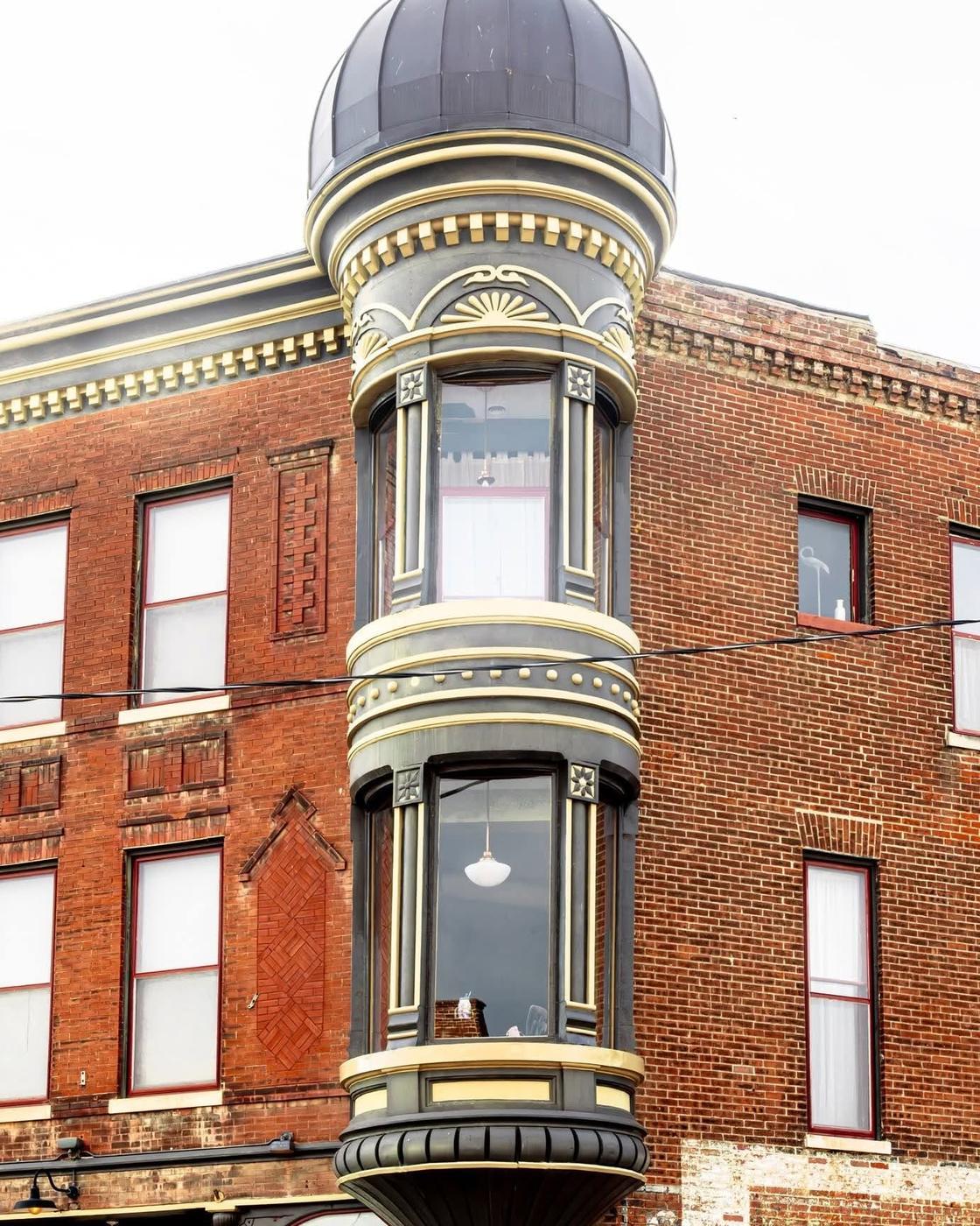 The corner of the building: a domed oriel turret painted slate and cream over red brick, with fan and shell ornament.